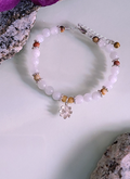 A bracelet with moonstone, crazy lace agate, and silver strung on silver wire adorned with a silver daisy charm.